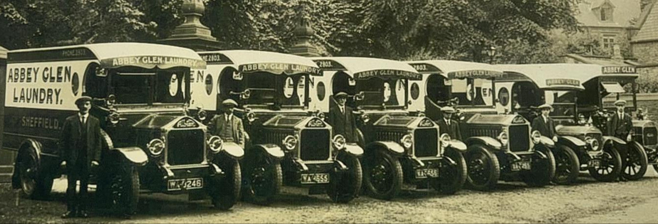 Vintage black and white photograph of Abbey Glen Laundry trucks lined up outdoors.
